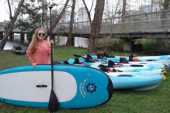 A woman standing near SUPs and kayaks